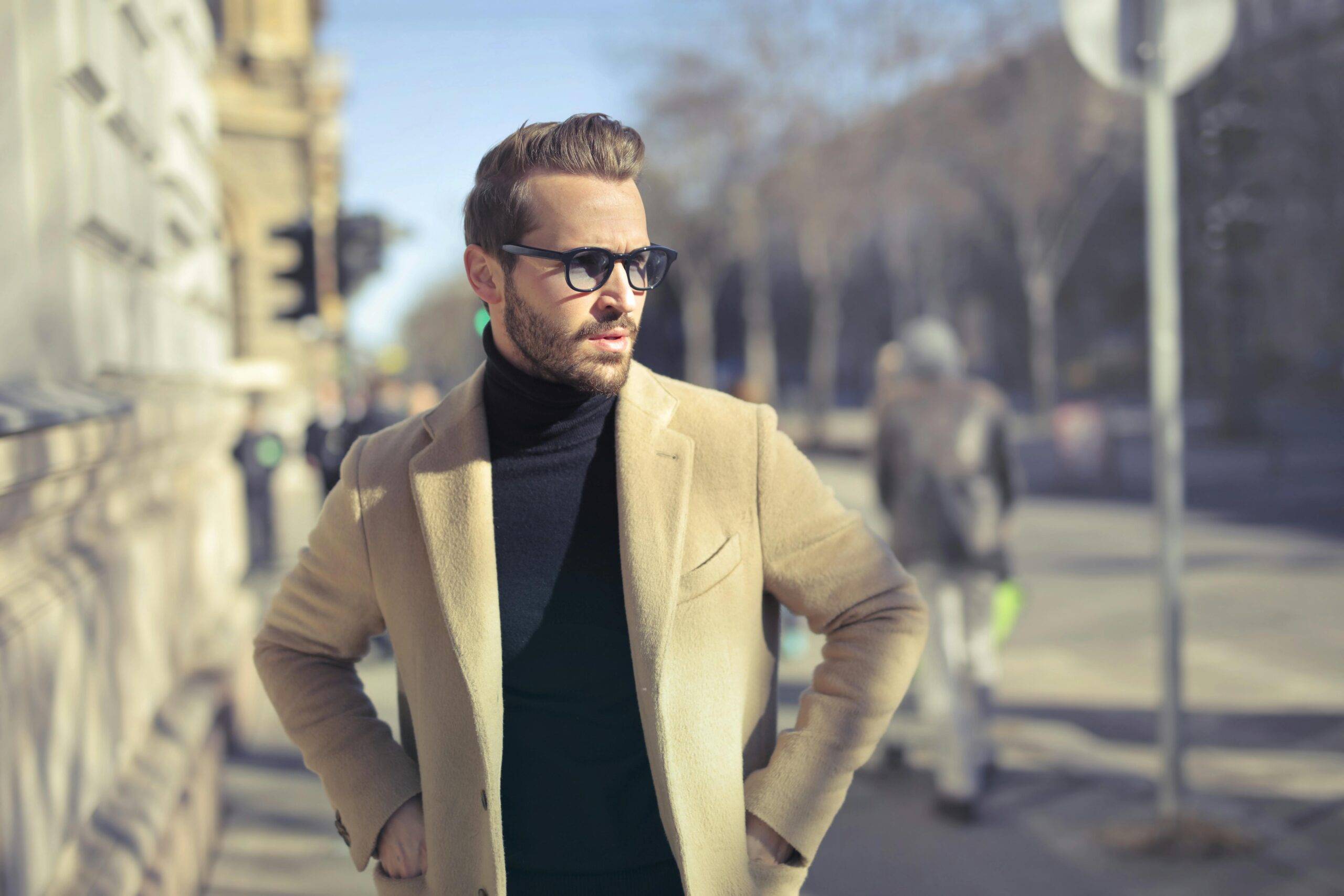 Stylish man in glasses and coat posing outdoors on an urban street in Budapest.